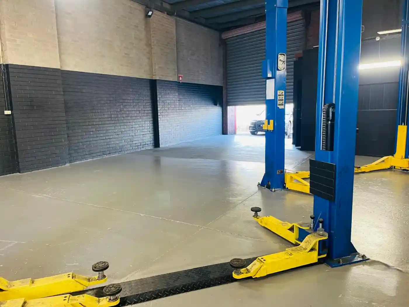 Clear workshop floor with hoist arms lowered, ready for the next vehicle