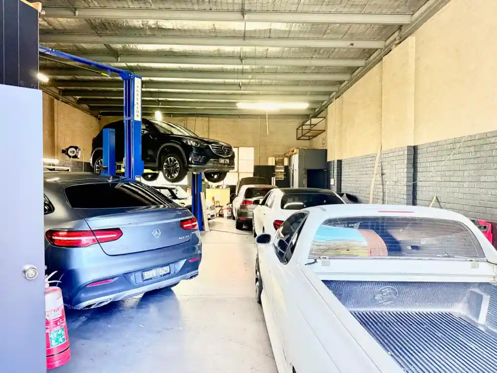 Mercedes-AMG GLE 43 alongside a Mazda CX-5 raised on a hoist, looking down the length of the workshop
