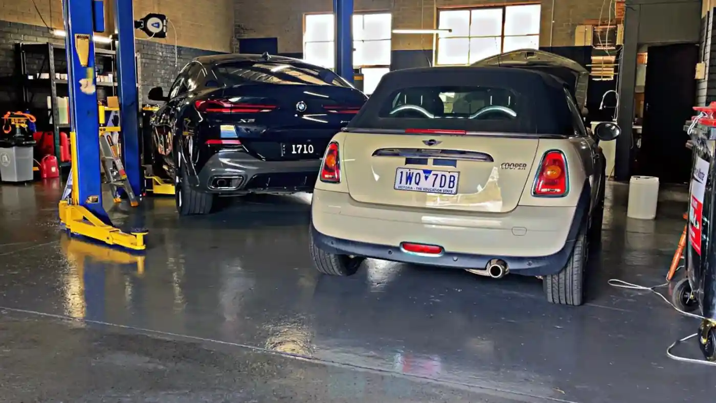 BMW X6 and a Mini Cooper convertible in adjacent service bays